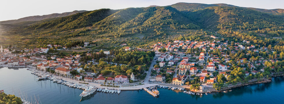 Aerial view of the old town, where terracotta roofs meet the azure harbor dotted with yachts, nestled against lush green hills, Stari Grad, Split-Dalmatia County, Croatia.