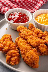 Fried chicken breast strips on grey table background. Delicious chicken crisps
