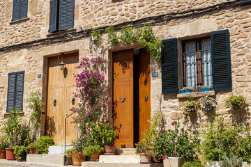 Traditional Stone Facade of a Mediterranean House Entrance Decorated with Numerous Flower Pots