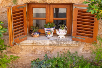 Traditional Mediterranean Window with Open Wooden Shutters and Succulent Plants on the Windowsill