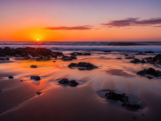 Vibrant sunset over rocky beach with ocean waves and dramatic sky