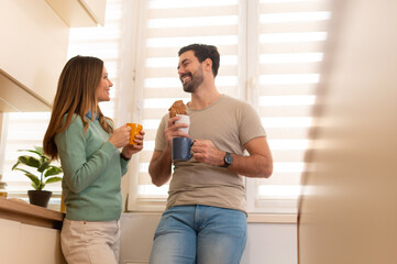Happy couple enjoying morning coffee and pastry in kitchen