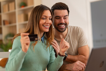 Happy couple shopping online using credit card