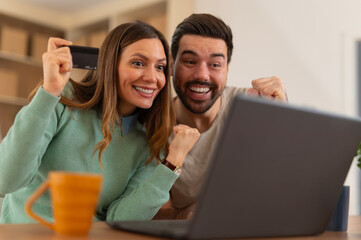 Happy couple successfully shopping online with credit card