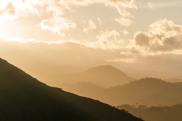 Obraz premium Atmospheric Golden Haze and Silhouetted Hills in the Tropical Mountains