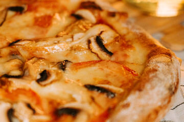 Enjoying a slice of pizza with cheese, chicken, and mushrooms in a cozy setting after dinner