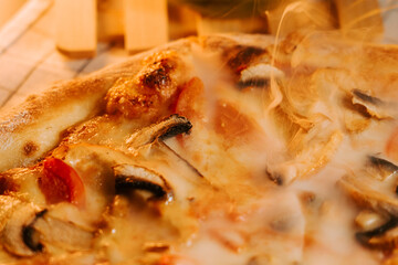 Freshly baked pizza with cheese, chicken, and mushrooms on a wooden surface