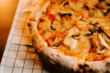Delicious pizza with cheese, chicken, and mushrooms on a checkered cloth table