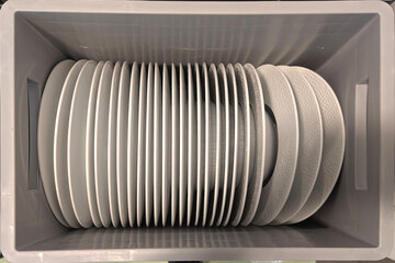 Plates arranged in storage bins at a restaurant kitchen during busy lunch hours. Catering for events and receptions concept.