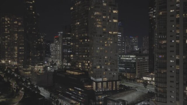 Aerial panoramic night view of Parque La Mexicana and the surrounding residential and corporate towers in Mexico City. The drone flies backwards to reveal the city. Shot on D-Log