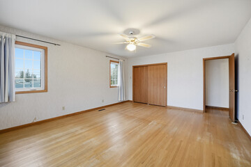 Large, empty room with a wooden floor and a white wall