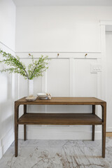 Wooden table with a vase of green leaves on it
