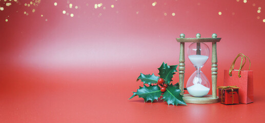  Hourglass Beside a Shopping Bag and Wrapped Gift on Red Surface &ndash; Minimalist Christmas Shopping Concept with Copy Space for Seasonal Offers