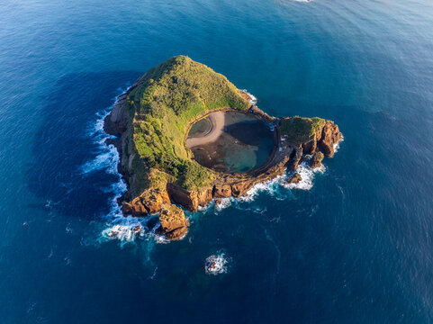 Aerial view of a volcanic islet cradling a serene crater lake amidst the vast, boundless ocean, Ilheu de Vila Franca do Campo, Vila Franca do Campo, Azores, Portugal.