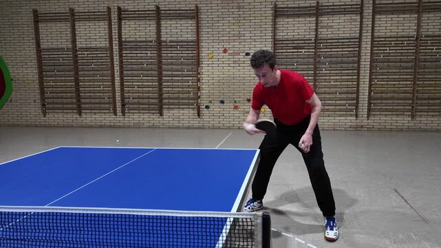 A professional table tennis player makes a backhand shot during practice on a blue table, table tennis, slow motion