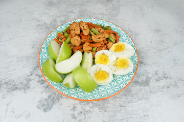 Healthy balanced meal with sautéed vegetables, seasoned chicken, sliced green apples, and boiled eggs. Clean eating, high-protein, low-carb diet plate on a textured background.