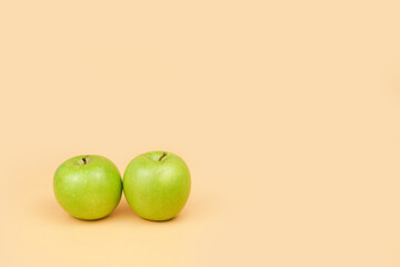 Two green apples on a pastel background with clean copy space, representing healthy eating, nutrition choices, minimal lifestyle, and fresh organic food concepts.