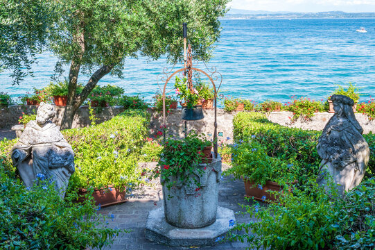 charming garden terrace overlooking Lake Garda featuring an old stone well adorned with flowers