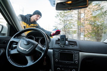 view from driver seat showing man outside cleaning front glass while interior instruments and...