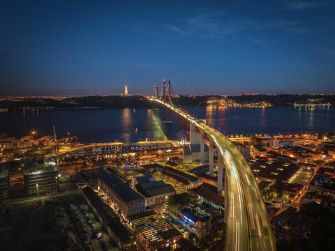 Aerial view of the Ponte 25 de Abril bridge stretching over the Tagus River, lights blurring as they streak across, Lisbon, Lisbon, Portugal.