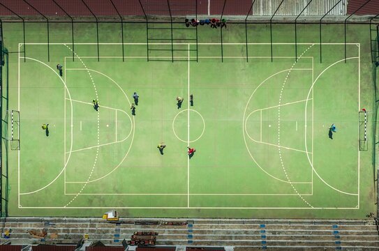 Aerial view of a vibrant green futsal court where players in colorful jerseys engage in a lively match, Lisbon, Lisbon, Portugal.