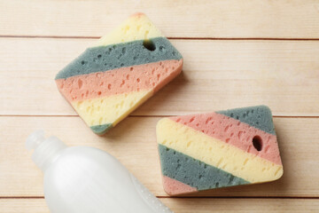 Clean kitchen sponges and dish soap on wooden table, flat lay