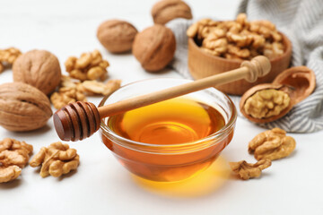 Sweet honey with walnuts and dipper on white table, closeup
