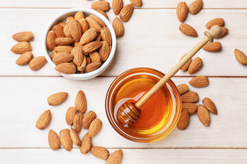 Honey with almond nuts and dipper on wooden table, flat lay