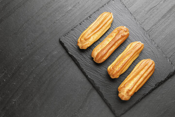 Tasty eclairs on black table, top view. Space for text