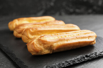 Tasty eclairs on black table, closeup. Delicious dessert