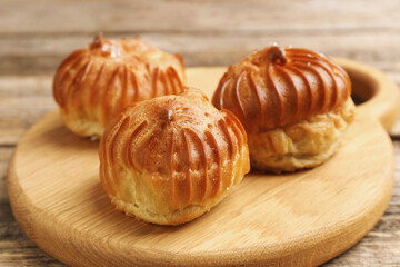 Tasty profiteroles on wooden table, closeup. Delicious dessert