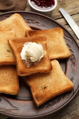 Slices of toasted bread, butter and jam on wooden table, closeup