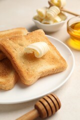Slices of toasted bread, butter and honey on beige table, closeup