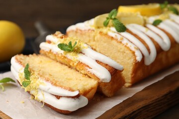Delicious lemon cake with glaze, fresh fruit slices and mint on table, closeup