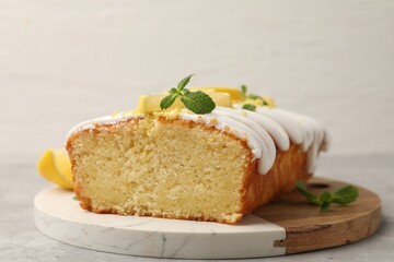 Delicious lemon cake with glaze, fresh fruit slices and mint on gray table, closeup