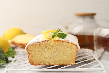 Delicious lemon cake with glaze, fresh fruit slices and mint on light table, closeup