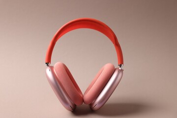 Pair of stylish headphones on beige background, closeup