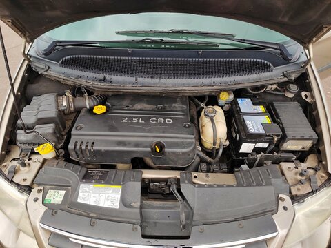 Belarus, Svetlogorsk, July 10, 2025. Servicing diesel car engine with open hood showing components. Inspecting 2.5L CRD diesel engine under open hood with visible battery and fluid caps during mainten
