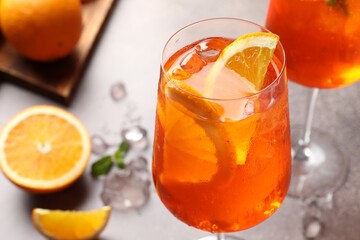 Glasses of refreshing spritzer cocktail and oranges on grey table, closeup