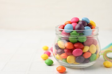 Delicious colorful candies on white tiled table, closeup. Space for text