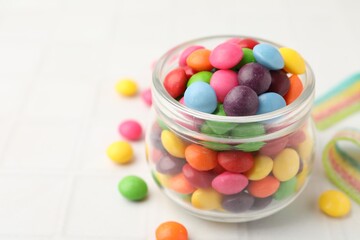 Delicious colorful candies on white tiled table, closeup. Space for text