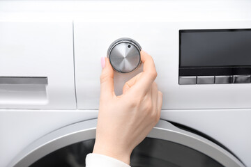 Woman turning on white washing machine, closeup