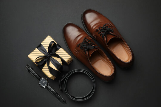 Beautiful wrapped gift box and men's accessories on black background, flat lay - Powered by Adobe