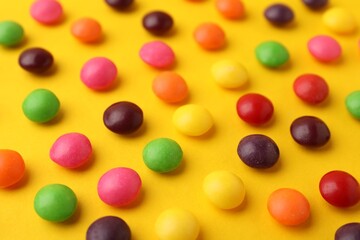 Delicious colorful candies on yellow background, closeup