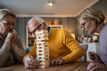 Seniors playing jenga game with friends at home