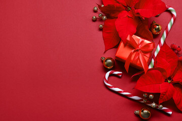 Beautiful poinsettia flowers and Christmas decor on red background, flat lay. Space for text