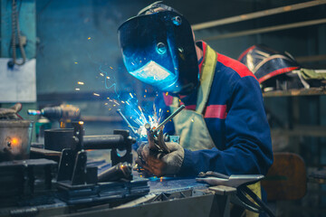 Candid photo welder at workbench doing welding of metal parts. Workflow in the Train Spare Parts...
