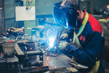 Candid photo welder at workbench doing welding of metal parts. Workflow in the Train Spare Parts...