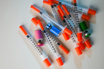 Close up of Pile of Single Use Syringes with Orange Safety Tips and Glass Vials