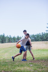 Fototapeta premium Teenagers Playing Outdoor Basketball in Mountain Landscape